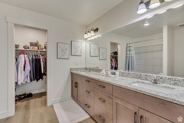 full bath featuring double vanity, a spacious closet, visible vents, and a sink