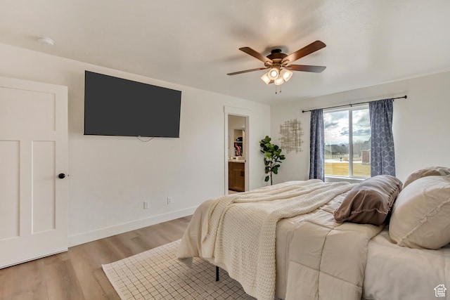 bedroom with connected bathroom, baseboards, ceiling fan, and light wood finished floors