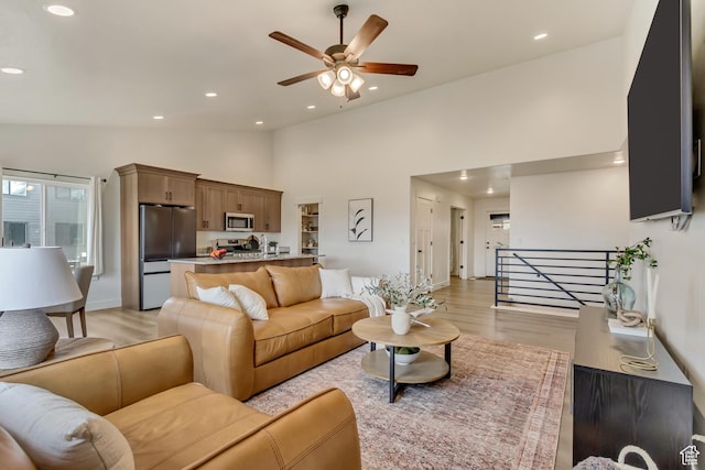 living area featuring light wood-type flooring, ceiling fan, high vaulted ceiling, and recessed lighting