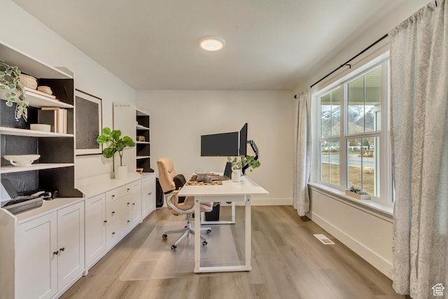home office with visible vents, light wood-style flooring, and baseboards