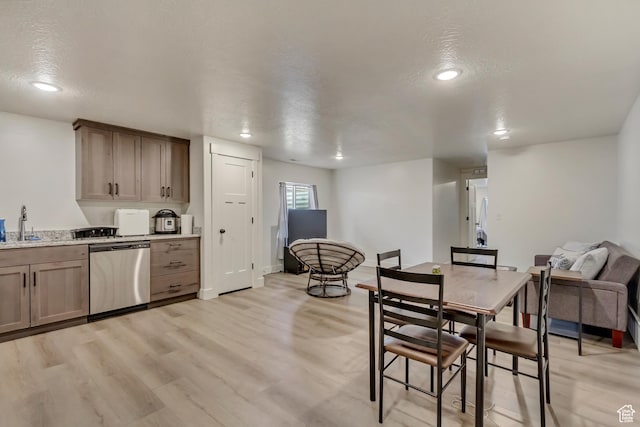 kitchen featuring dishwasher, light wood-style flooring, a textured ceiling, a sink, and recessed lighting