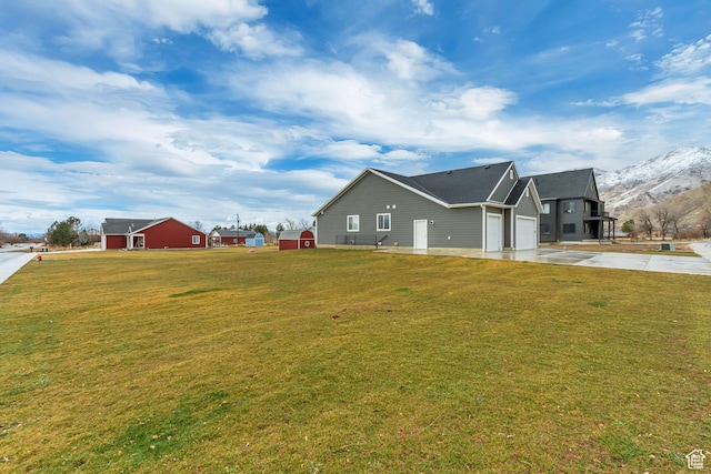 view of property exterior featuring driveway, a lawn, an attached garage, and a mountain view