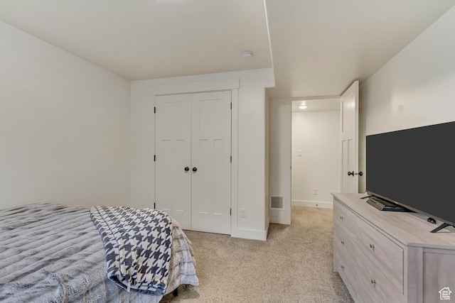 bedroom with a closet, light colored carpet, visible vents, and baseboards