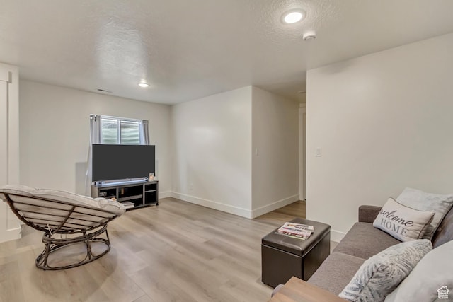 interior space featuring baseboards, visible vents, light wood finished floors, and a textured ceiling