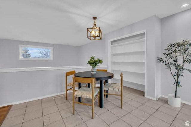 dining area with light tile patterned floors, built in shelves, an inviting chandelier, and baseboards