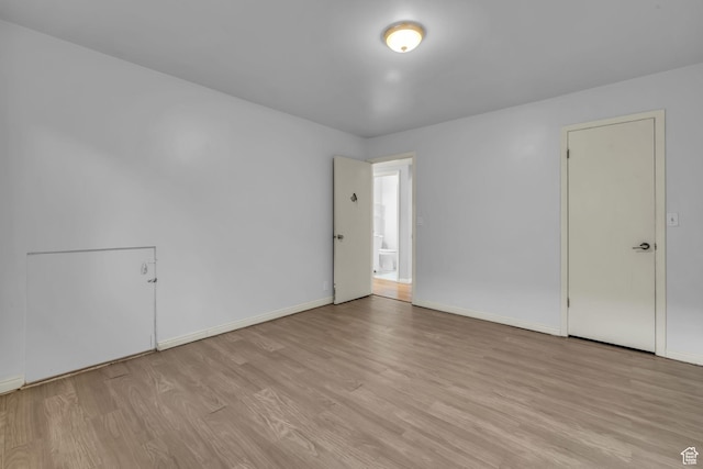 spare room featuring baseboards and light wood finished floors