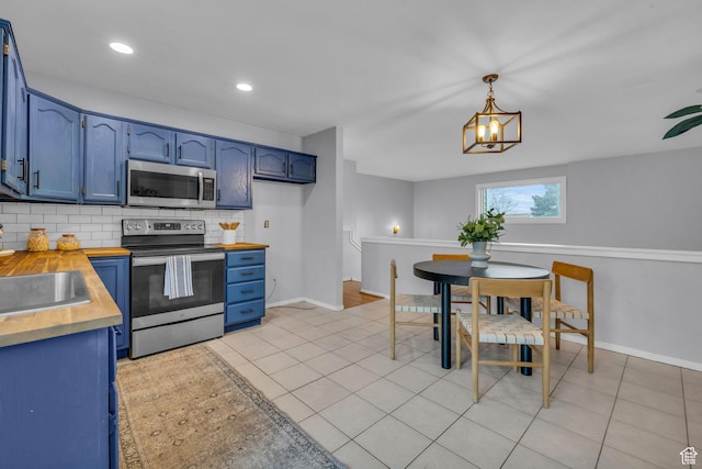 kitchen featuring blue cabinets, wood counters, appliances with stainless steel finishes, and backsplash