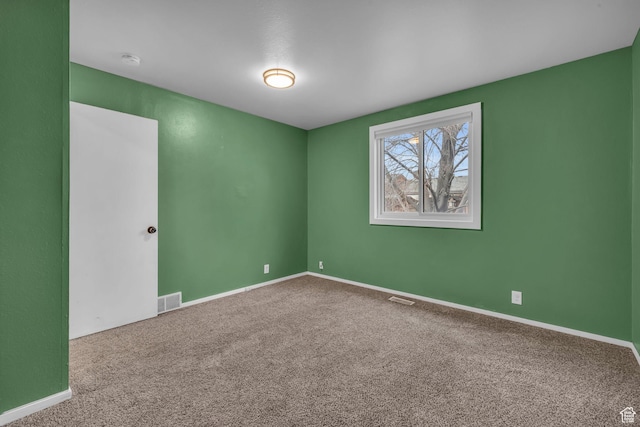 spare room featuring carpet floors, visible vents, and baseboards