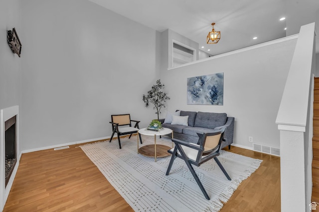 sitting room with baseboards, a towering ceiling, visible vents, and light wood-style floors