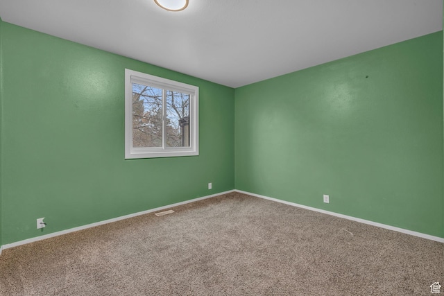 unfurnished room with carpet, visible vents, and baseboards