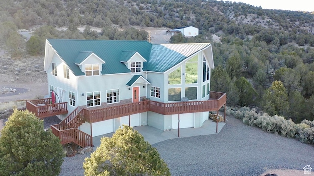 view of front facade featuring stairway, an attached garage, metal roof, a wooded view, and driveway