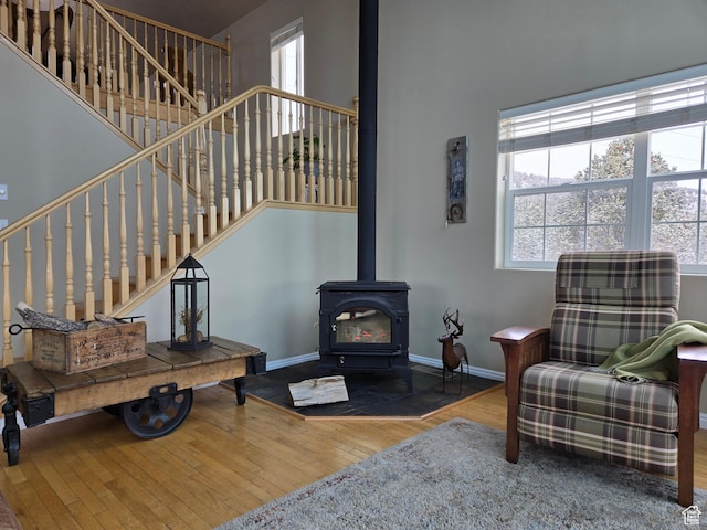living room with a wood stove, a wealth of natural light, a high ceiling, and hardwood / wood-style floors