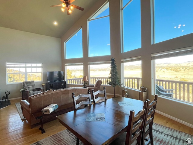 dining room with high vaulted ceiling, ceiling fan, baseboards, and wood finished floors