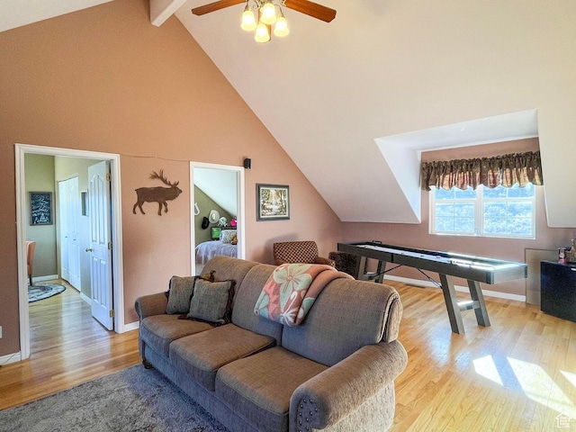 living room with high vaulted ceiling, a ceiling fan, baseboards, light wood-type flooring, and beamed ceiling