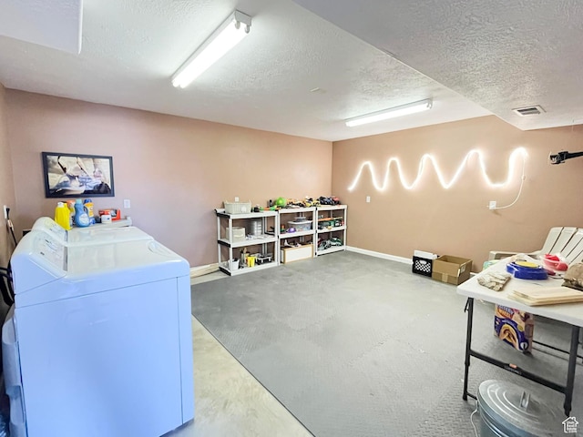 interior space with baseboards, visible vents, a textured ceiling, and washing machine and clothes dryer