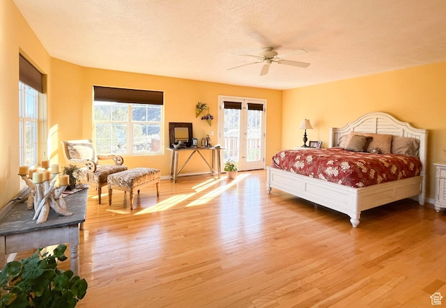 bedroom featuring light wood finished floors, a ceiling fan, access to outside, a textured ceiling, and french doors
