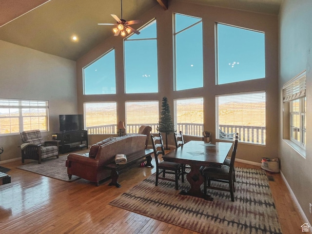 dining area with high vaulted ceiling, wood-type flooring, and baseboards