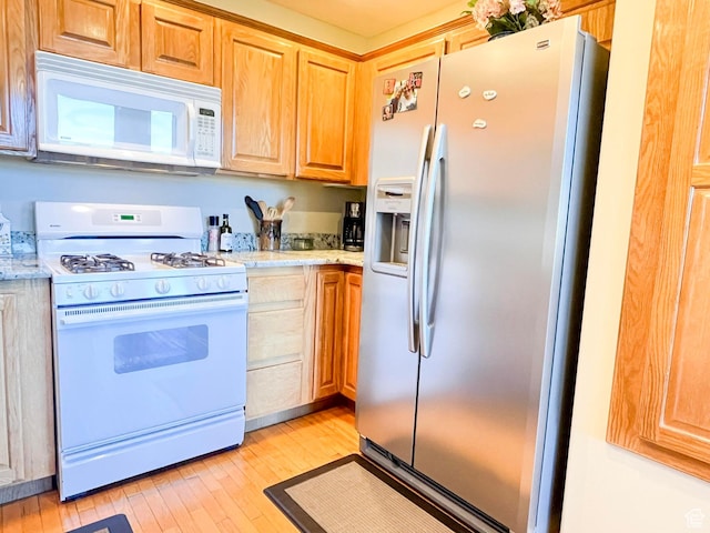 kitchen with light stone countertops, white appliances, light brown cabinets, and light wood-style floors