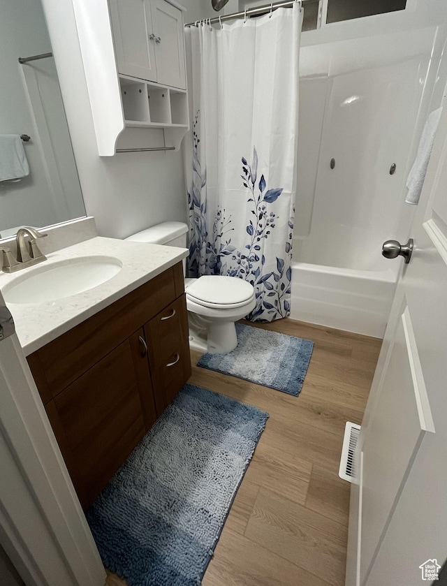 bathroom with wood finished floors, toilet, vanity, and shower / tub combo