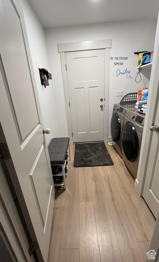 clothes washing area featuring washing machine and clothes dryer and light wood-style flooring