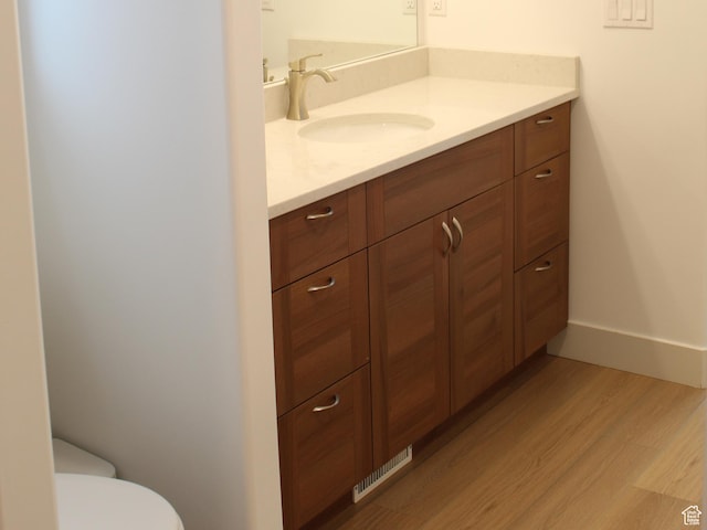 bathroom with vanity, wood finished floors, toilet, and baseboards