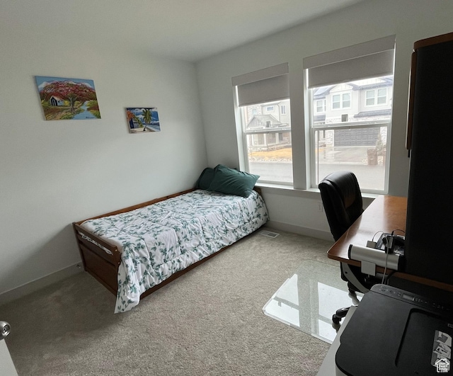 carpeted bedroom featuring a desk and baseboards