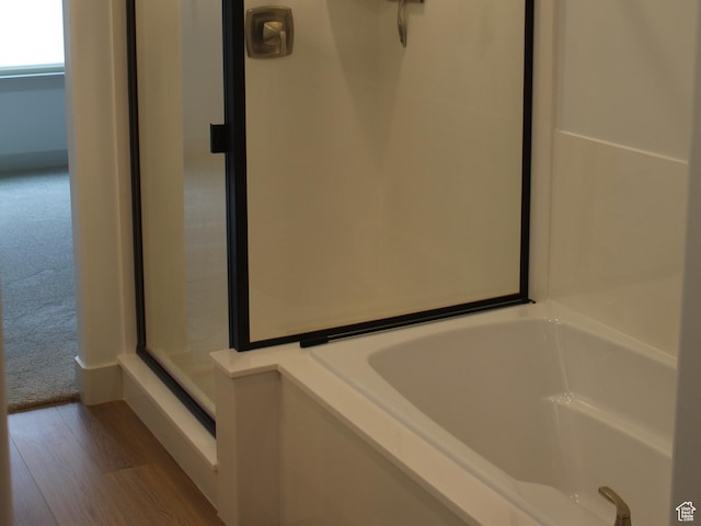 full bathroom featuring a bath and wood finished floors