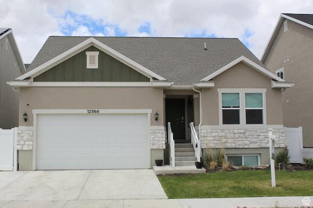 view of front of property featuring stone siding, roof with shingles, and driveway