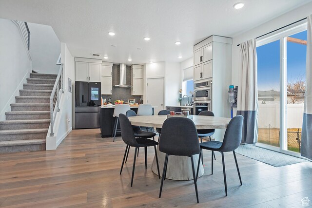 dining area with stairs, a wealth of natural light, recessed lighting, and wood finished floors