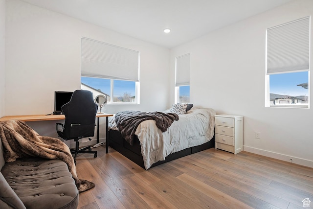 bedroom with light wood finished floors, multiple windows, baseboards, and recessed lighting