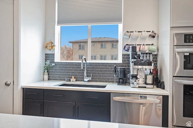 kitchen featuring appliances with stainless steel finishes, backsplash, a sink, and light countertops