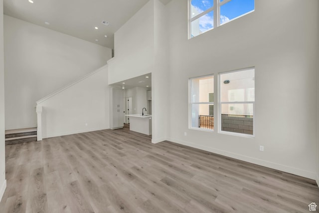 560 W Aqua Cv Unit 506, St George, UT 84790 - unfurnished living room with recessed lighting, a towering ceiling, light wood-style floors, a sink, and baseboards