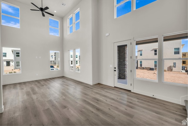 unfurnished living room featuring a ceiling fan, baseboards, visible vents, and wood finished floors