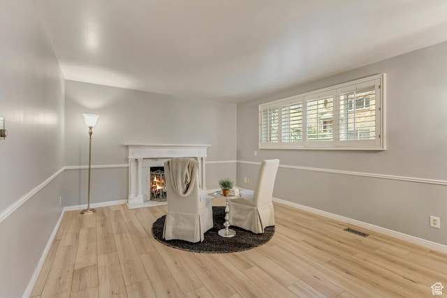 unfurnished room with a fireplace with flush hearth, visible vents, baseboards, and wood finished floors