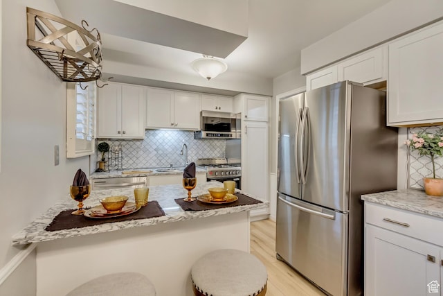 kitchen featuring appliances with stainless steel finishes, light wood-type flooring, a sink, and white cabinets