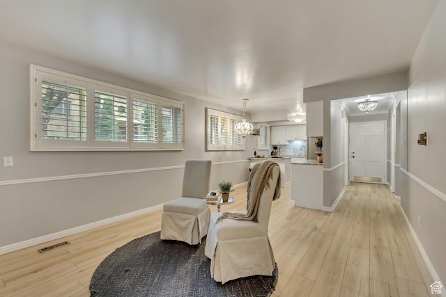 sitting room featuring light wood-style floors, visible vents, a notable chandelier, and baseboards