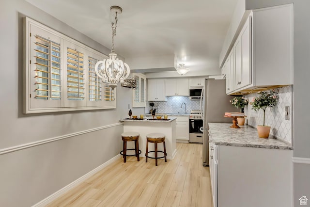kitchen featuring a breakfast bar, light wood finished floors, backsplash, a sink, and a peninsula