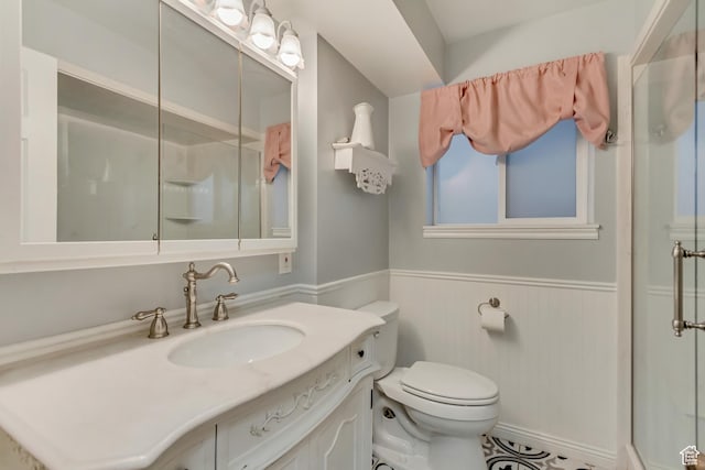 full bathroom featuring wainscoting, a shower stall, toilet, and vanity