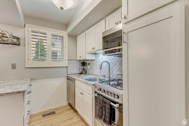 kitchen with white cabinets, backsplash, stainless steel appliances, and a sink