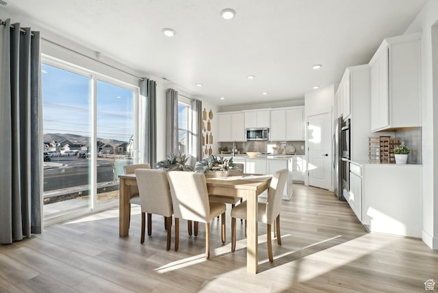 dining area with light wood-type flooring and recessed lighting