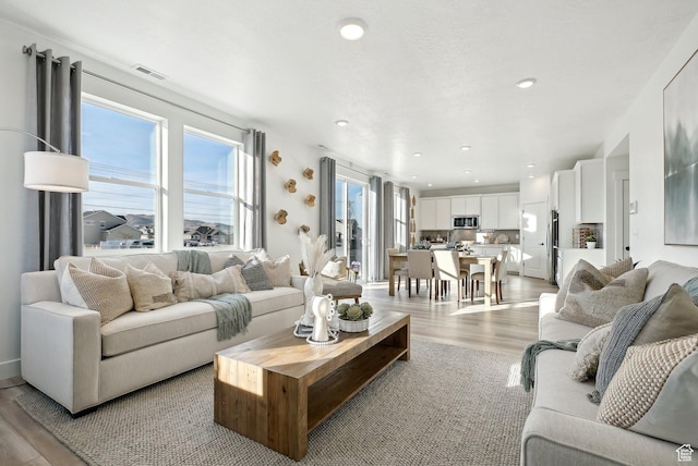 living area featuring recessed lighting, light wood-type flooring, and visible vents
