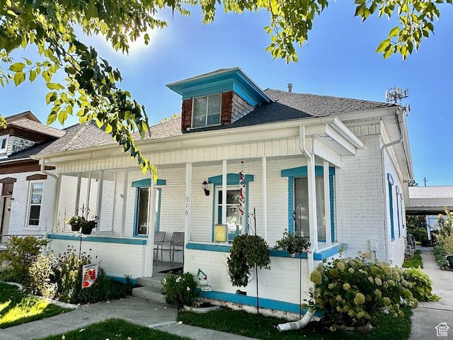 bungalow-style home with brick siding, roof with shingles, and a porch