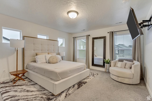 bedroom with a textured ceiling, carpet flooring, visible vents, and baseboards
