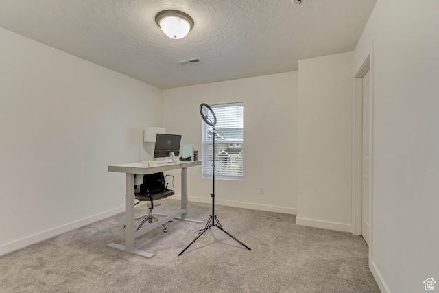 home office featuring a textured ceiling, carpet flooring, and baseboards