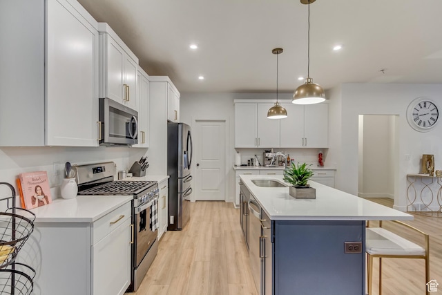 kitchen featuring a breakfast bar, stainless steel appliances, light countertops, white cabinetry, and an island with sink
