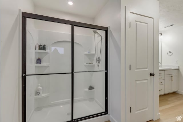 full bathroom with visible vents, a shower stall, vanity, and wood finished floors