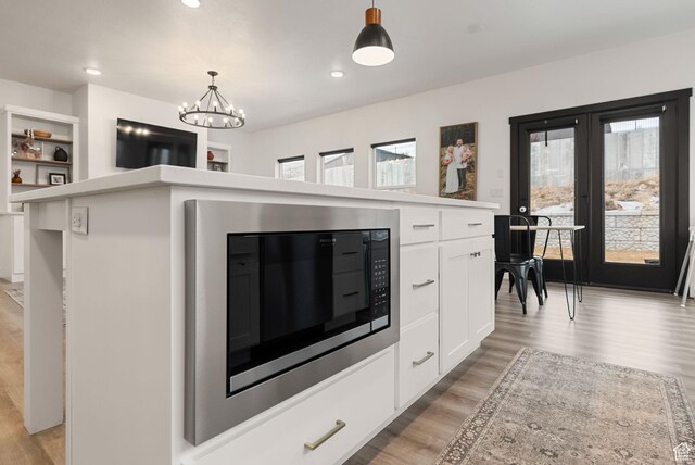628 S 1080 E, Smithfield, UT 84335 - kitchen featuring built in microwave, light wood-style floors, hanging light fixtures, white cabinets, and a chandelier