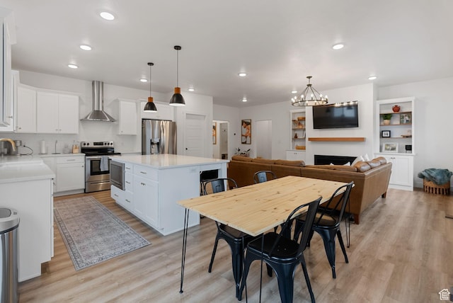628 S 1080 E, Smithfield, UT 84335 - kitchen featuring appliances with stainless steel finishes, wall chimney range hood, light wood-style flooring, a kitchen island, and a chandelier