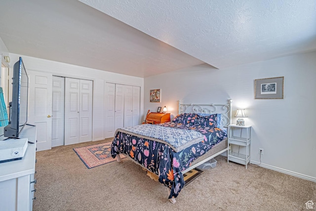 bedroom with carpet, a textured ceiling, baseboards, and two closets