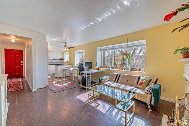 living area featuring a fireplace, a textured ceiling, baseboards, and wood finished floors